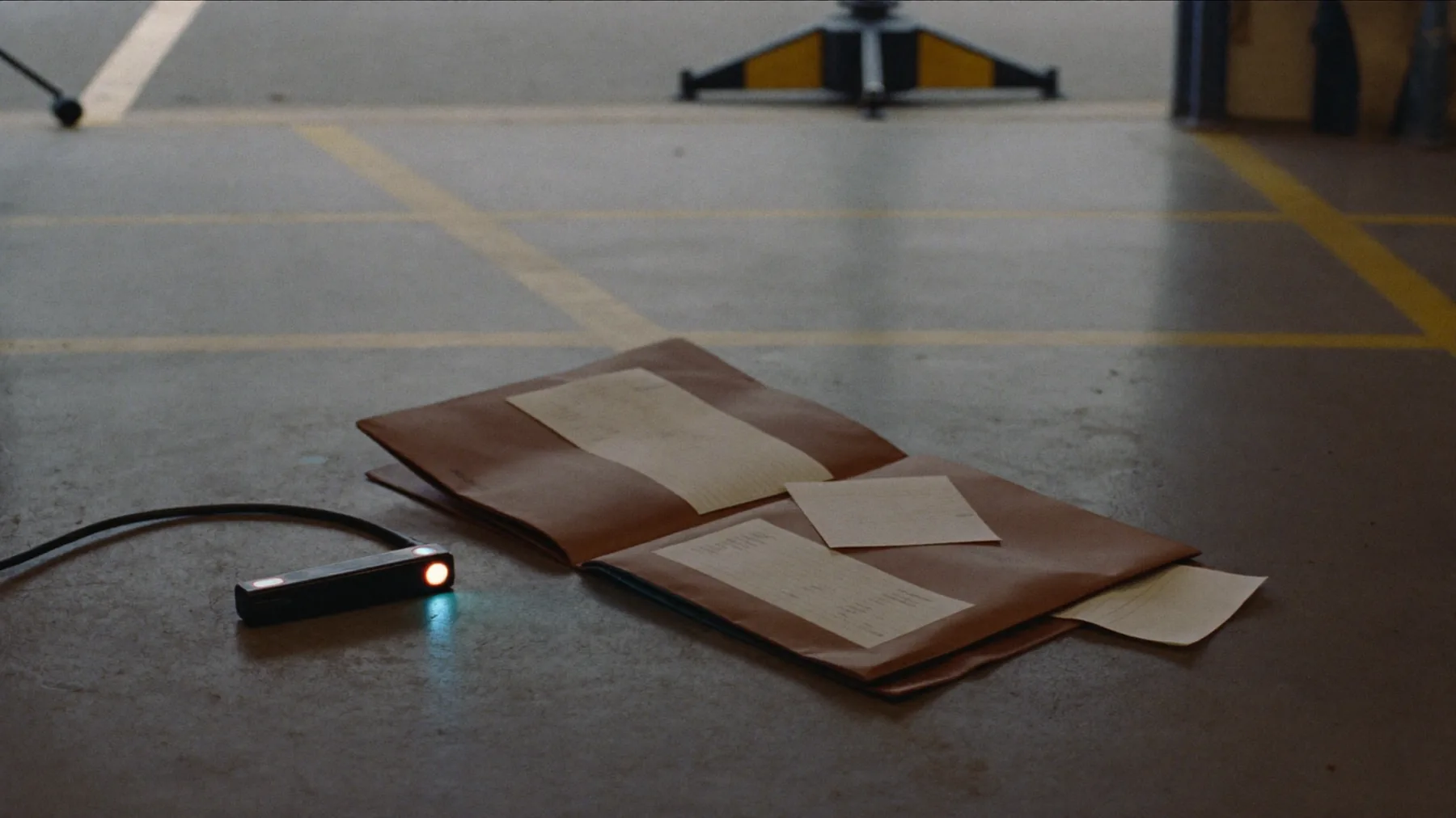 An inspection torch switched on and a thick service history folder with receipts spilling out of it, on a cold concrete garage floor